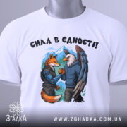 Футболка сила в єдності, біла, зображена зверху, фон світло-сірий, принт з лисицею та орлом, які стискають руки, на лисиці броня, на орлі светр, на футболці є етикетка.