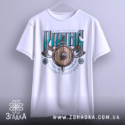 Футболка сила вікінга, біла, підвішена на вішалці, фон світло-сірий, принт з написом 'VIKING' у зелених та чорних кольорах, з зображенням щита та сокири.