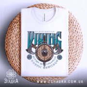 Футболка сила вікінга, біла, складена на плетеному кошику, фон світло-сірий, принт з написом 'VIKING' у зелених та чорних кольорах, з зображенням щита та сокири.