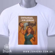 Футболка сильніша ніж думаю, біла, складена на столі, фон світло-сірий, принт з жінкою та чоловіком, з написом 'СИЛЬНІША, НІЖ ДУМАЮ', на футболці є етикетка з зеленим шнурком.
