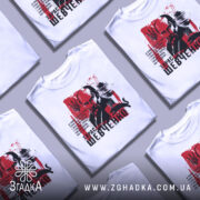 Футболка Тарас Шевченко білого кольору, зображена з фронтального ракурсу на манекені, фон нейтральний, принт містить портрет Тараса Шевченка на червоному фоні з текстом.