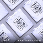 Футболка тато чоловік білого кольору, зображена з фронтального ракурсу на манекені, фон світло-сірий, принт чорного кольору з написом 'TATO чоловік №1 Самий кращий у світі'.