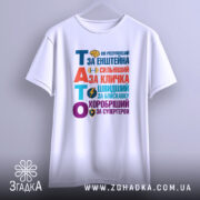 Футболка тато герой для дітей, біла, зображена з фронтального ракурсу на манекені, фон світло-сірий, принт кольоровий з текстом "ТАТО" та різними іконками, що підкреслюють його значення.