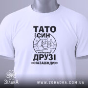 Футболка тато і син білого кольору, складена на поверхні, фон світло-сірий, принт чорного кольору з написом 'ТАТО і СИН найкращі ДРУЗІ назавжди' та малюнком рук, що стискаються, з зеленим ярликом.