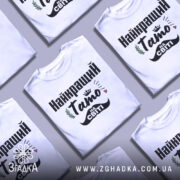 Футболка тато на світі — кілька складених футболок, композиція на столі.