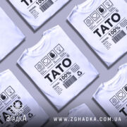 Футболка тато органічний подарунок, біла, складена в кілька шарів на фоні сірого кольору, принт чорного кольору з текстом і символами.