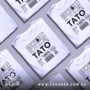 Футболка тато органічний, білого кольору, зображена на манекені з правого ракурсу, фон світло-сірий, принт містить чорний текст і символи, що описують склад та особливості футболки.