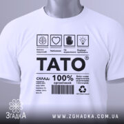 Футболка тато органічний, білого кольору, складена на плоскій поверхні, фон світло-сірий, принт чорного кольору з текстом і символами, на комірці є етикетка з зеленим шнурком.