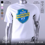 Футболка тато розрулить усе, білого кольору, зображена на манекені з легким боковим ракурсом, фон нейтральний, принт у вигляді синього щита з жовтою стрічкою та текстом.