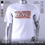 Футболка тато білого кольору, зображена з фронтального ракурсу на манекені, фон світло-сірий, принт з написом 'TATO' в декоративному стилі з рослинними елементами.