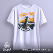 Футболка this is fine, біла, підвішена на вішалці, фон світло-сірий, принт з собакою на фоні двох автомобілів, яскраві кольори: оранжевий, чорний, жовтий.