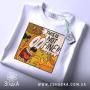 Футболка this is not fine, білого кольору, складена на поверхні, фон світло-сірий, принт з коміксним персонажем, що кричить з написом 'THIS IS NOT FINE!!', на комірці є етикетка.