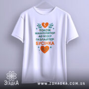 Футболка токсік бусінка, біла, зображена на вішалці, фон градієнтний сірий, принт містить текст у зеленому та оранжевому кольорах, з серцем та рослинними елементами.