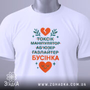 Футболка токсік бусінка, біла, зображена зверху, фон світлий, принт з текстом у зеленому та оранжевому кольорах, з серцем та рослинними елементами, на комірці є етикетка.