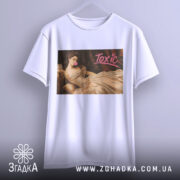 Футболка токсік білого кольору, підвішена на вішалці, з принтом, що зображує жінку в елегантній сукні, яка жує жувальну гумку. Принт має яскравий напис 'Toxic'.