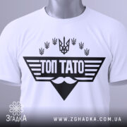 Футболка топ тато білого кольору, складена на поверхні, з видимим етикеткою, фон світлий, принт чорного кольору з написом 'ТОП ТАТО' та символікою України.