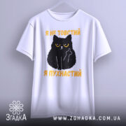 Футболка товстий пухнастий, біла, зображена з фронтального ракурсу, на фоні світло-сірого кольору, принт з чорним котом з жовтими очима та текстом "Я не товстий, я пухнастий" у жовтому кольорі.