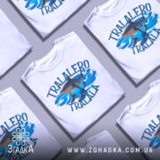 Футболка tralalero tralala, білого кольору, зображена з ракурсу спереду на манекені, фон світлий, принт з акулами та кросівками на блакитних хвилях.