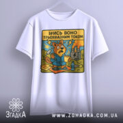 Футболка трьохфазний гумор. Біла футболка, підвішена на вішалці, з принтом бобра в синьому халаті, який тримає чашку. Принт яскравий, з жовтим текстом, на фоні електричної станції.