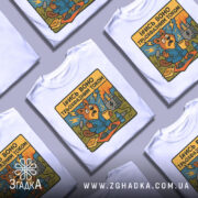 Футболка трьохфазний гумор. Біла футболка на манекені, з принтом, що зображує бобра в синьому халаті, який тримає чашку, на фоні електричної станції з димом і блискавками. Принт яскравий, з жовтим текстом.