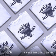 Футболка трохи за*бався, біла, зображена з правого ракурсу на манекені, фон світло-сірий, принт з чорним малюнком голови динозавра та написом 'ТРОХИ ЗАБ'АВСЯ' у трикутнику з зірками.