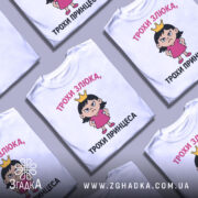 Футболка трохи злюка, біла, зображена з фронтального ракурсу на манекені, фон світло-сірий, принт з дівчинкою в короні та написом 'ТРОХИ ЗЛЮКА, ТРОХИ ПРИНЦЕСА'.