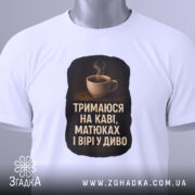 Футболка тримаюся на каві, білого кольору, зображена на манекені з правого боку, фон світло-сірий, принт з чашкою кави та текстом на чорному фоні.