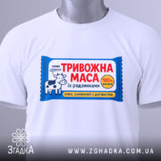 Футболка тривожна маса білого кольору, зображена з фронтального ракурсу на манекені, фон нейтральний, принт яскравий, з коровою та текстом "ТРИВОЖНА МАСА".