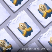 Футболка тризуб золото, біла, зображена з фронтального ракурсу на манекені, фон градієнтний сірий, принт з тризубом у золотих та блакитних тонах, з ефектом світла.