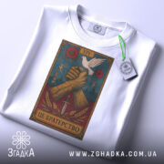 Футболка це братерство, складена біла футболка з принтом, на якому зображені дві з'єднані руки, що тримають меч, а над ними літає голуб, фон принта темно-синій з червоними квітами, на футболці є етикетка з зеленим шнурком.