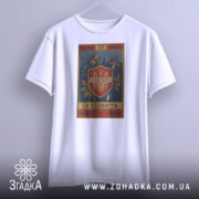 Футболка це гідність. Біла футболка з коротким рукавом, підвішена на вішалці, з видимим принтом герба України. Фон світло-сірий, а принт містить рослинні елементи та напис 'ЦЕ ГІДНІСТЬ'.
