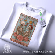 Футболка це кохання. Біла футболка, на якій видно принт з двома скелетами, що спілкуються, з квітами в руках. На футболці також є етикетка з зеленим шнурком.