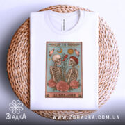 Футболка це кохання. Біла футболка, складена на плетеній кошику, з принтом, на якому зображені два скелети, що тримають квіти. Принт оформлений у ніжних кольорах з елементами природи.