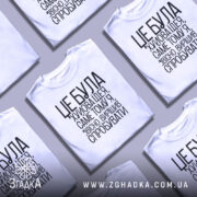 Футболка це погана ідея. Біла футболка на манекені, з чорним принтом, що містить текст. Фон світло-сірий, деталі принта чітко видимі, текст розташований вертикально.