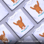 Футболка твори добро. Біла футболка з коротким рукавом, зображення ведмедя, що піднімає руки вгору, на грудях напис "БРО ТВОРИ ДОБРО", під ним текст "БО ДОБРО ПЕРЕМАГАЄ ЗЛО!", фон нейтральний, акцент на принті.