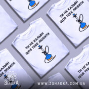 Футболка ти не кальян. Біла футболка з коротким рукавом, зображена з фронтального ракурсу. На грудях великий принт з текстом 'ТИ НЕ КАЛЬЯН ЩОБ ТЕБЕ ЛЮБИТИ' та малюнком кальяну, виконаним у синіх та чорних кольорах. Фон світлий, з легким градієнтом.