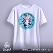 Футболка ти ж моя курочка. Біла футболка, підвішена на вішалці, з круглим принтом курки на блакитному фоні. Принт оточений чорними хрестами. Фон світлий, з легким градієнтом.