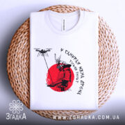 Футболка у самурая нема дрона. Біла футболка, складена на плетеній основі, принт самурая на червоному фоні, деталі принта чіткі, фон натуральний, з текстурою.