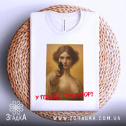 Футболка у тебе генератор. Біла футболка, складена на плетеній кошику, принт з жінкою з пістолетом, знімок з верхнього ракурсу, фон світлий, текст червоним кольором, футболка виглядає акуратно.