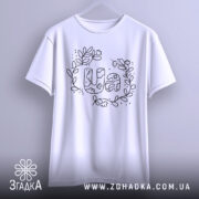 Футболка UA квіти, біла, підвішена на вішалці, з фронтального ракурсу, фон світло-сірий, принт з написом UA в оточенні квітів і листя, виконаний чорним кольором.