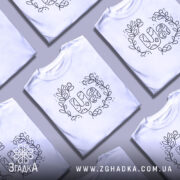 Футболка UA квіти, біла, зображена на манекені з правого боку, фон світло-сірий, принт з написом UA в оточенні квітів і листя, виконаний чорним кольором.