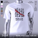 Футболка білого кольору, зображена на манекені, з принтом у вигляді гри хрестики-нулики, де червоною лінією закреслено одну з літер, текст під принтом говорить 'Вам, а не цензура'. Фон світлий, з легким градієнтом.