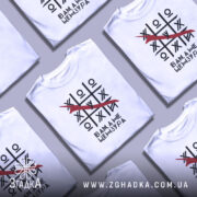 Футболка білого кольору, зображена на манекені, з принтом у вигляді гри хрестики-нулики, де червоною лінією закреслено одну з літер, текст під принтом говорить 'Вам, а не цензура'. Фон світлий, з легким градієнтом.