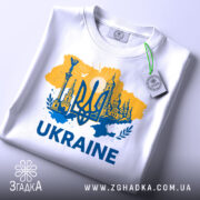 Футболка Україна тризуб, біла, зображена в плоскому вигляді, фон світло-сірий, принт жовто-блакитний з тризубом та архітектурними елементами, текст 'UKRAINE' великими буквами, на комірці є етикетка.