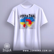 Футболка Україна білого кольору, підвішена на вішалці, з принтом червоних квітів на фоні синьо-жовтого кольору, ракурс спереду, фон світло-сірий.
