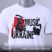 Футболка українська музика, біла, складена на столі, фон світло-сірий, принт з чорним текстом 'MUSIC UKRAINE' та гітарою, прикріплена етикетка з зеленим шнурком.