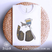 Футболка українська ППО білого кольору, складена на плетеному кошику, ракурс зверху, фон білий, принт з малюнком літака та будинків у сірих тонах, текст "ППО" у блакитному кольорі.