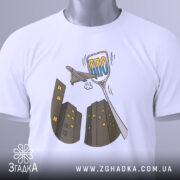 Футболка українська ППО білого кольору, складена на столі, ракурс зверху, фон світло-сірий, принт з малюнком літака та будинків у сірих тонах, текст "ППО" у блакитному кольорі, на комірці видна етикетка.