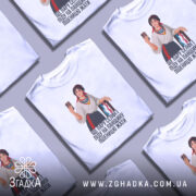 Футболка українська селфі красуня, біла, зображена з фронтального ракурсу, на фоні світло-сірого кольору, принт з дівчиною в національному вбранні, яка тримає телефон і посміхається, текст під малюнком: 'ЩЕ ПАРУ СЕЛФІ ПІДУ НА ПАНЦІЮ ПШЕНИЦЮ ЖАТИ'.