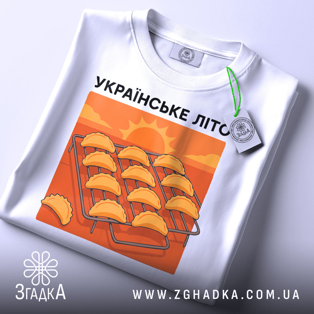 Футболка українське літо вареники, біла, складена на поверхні, фон білий, принт з варениками на решітці, тег на рукаві.